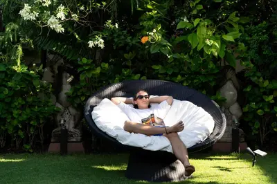 a man is sitting in a wicker chair at Villa Nyumpene in Legian in Legian