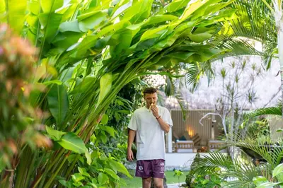 a man standing in a garden eating a banana at Villa Nyumpene in Legian in Legian