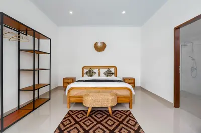 a bedroom with a bed and a chair in a room at Ageta Villa 3 bedrooms Umalas with pool in Kerobokan