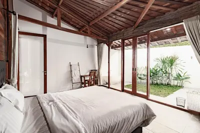 a bedroom with a bed and a large window at Cendani Private Pool Villa Bali in Kuta