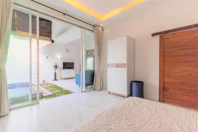 a bedroom with a bed and a large window at Cendani Private Pool Villa Bali in Kuta