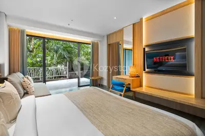 a bedroom with a bed and a television and a desk at Moriya by Kozystay - Nusa Dua in Nusa Dua