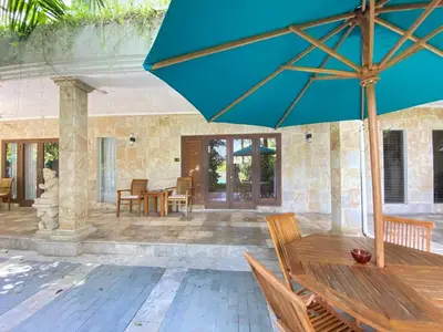 a patio with a wooden table and a blue umbrella at 2bedroom Apartment Petitenget Beach in Seminyak