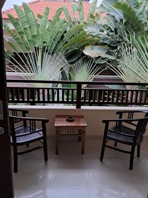 two chairs and a table in front of a large plant at SURFARIS INN on poppies 2 apartment in Legian