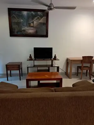 a living room with a couch and tables and a flat screen tv at SURFARIS INN on poppies 2 apartment in Legian