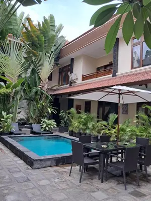 a patio with a table and chairs next to a pool at SURFARIS INN on poppies 2 apartment in Legian