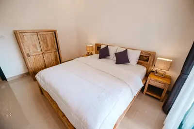a bedroom with a bed with white sheets and blue pillows at Kubu Dangin Guest House Kerobokan in Seminyak