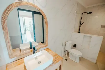 a bathroom with a sink and a toilet and a mirror at Kubu Dangin Guest House Kerobokan in Seminyak