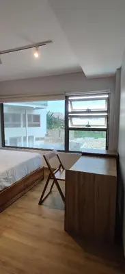 a bedroom with a bed and a desk and a window at HŌM Coliving Bali in Kerobokan