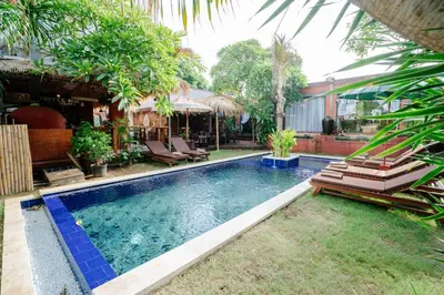 a swimming pool with lounge chairs in a backyard at The Saharah Mirage Bali in Kuta