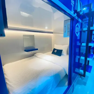 a bedroom with two beds in a room with blue lights at Rosalyne Sleepbox Denpasar Bali in Seminyak