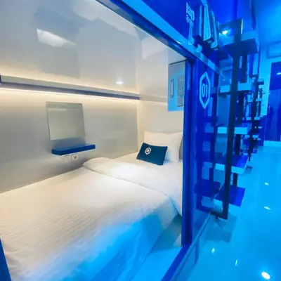 a small bedroom with a bed and a blue light at Rosalyne Sleepbox Denpasar Bali in Seminyak