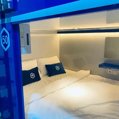a bedroom with a bed with two pillows on it at Rosalyne Sleepbox Denpasar Bali in Seminyak