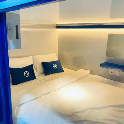 a bedroom with a large bed with blue pillows at Rosalyne Sleepbox Denpasar Bali in Seminyak