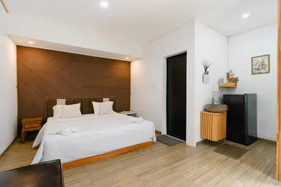 a bedroom with a large white bed with a wooden headboard at Griya Sadhana Dewi Sri in Legian