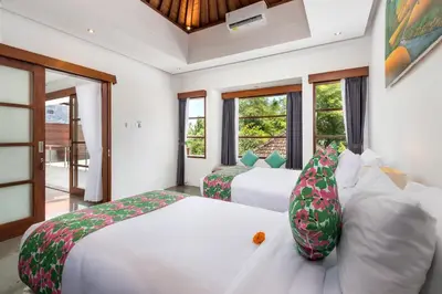 two beds in a room with windows at Villa Isabella in Seminyak