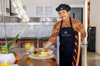 a woman standing in a kitchen with a plate of food at Villa Isabella in Seminyak