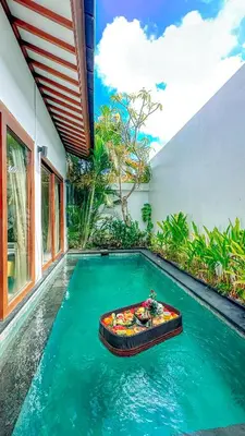 a pool with a bed in the middle of a house at Anari Villas Kuta by The Wina Resorts in Legian