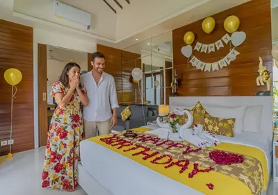 a man and woman standing next to a bed with a happy birthday cake at Anari Villas Kuta by The Wina Resorts in Legian