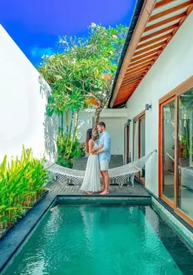a bride and groom standing next to a swimming pool at Anari Villas Kuta by The Wina Resorts in Legian