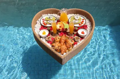 a tray of food in the shape of a heart next to a pool at The Medusa Villas Bali in Seminyak