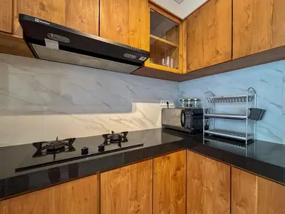 a kitchen with wooden cabinets and a stove top oven at Solvana Villas Sanur by AGATA in Sanur