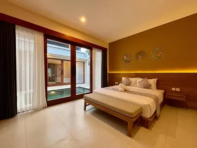 a bedroom with a bed and a large window at Solvana Villas Sanur by AGATA in Sanur