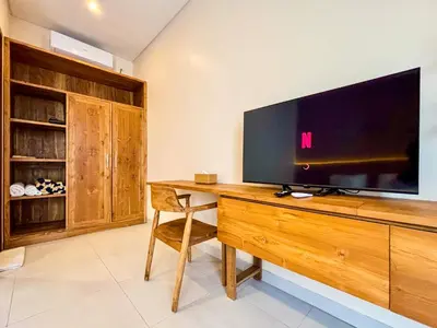 a living room with a television on a wooden desk at Solvana Villas Sanur by AGATA in Sanur
