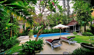 a patio with two chairs and an umbrella next to a pool at Villa bunny seminyak in Seminyak
