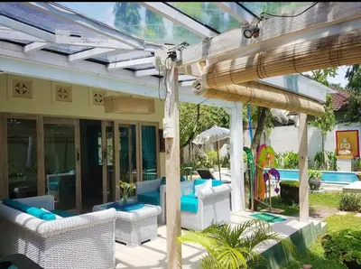 a patio with white wicker chairs and a pergola at Villa bunny seminyak in Seminyak