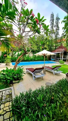 two lounge chairs and an umbrella next to a swimming pool at Villa bunny seminyak in Seminyak