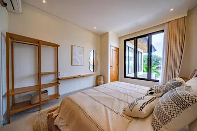 a bedroom with a bed with pillows and a window at Casa Samudra - 3BR Villa in Seminyak in Seminyak