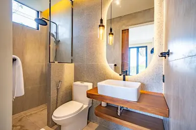 a bathroom with a sink and a toilet and a mirror at Casa Samudra - 3BR Villa in Seminyak in Seminyak
