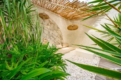 a room with a couch and some plants and a wall at Casa Samudra - 3BR Villa in Seminyak in Seminyak