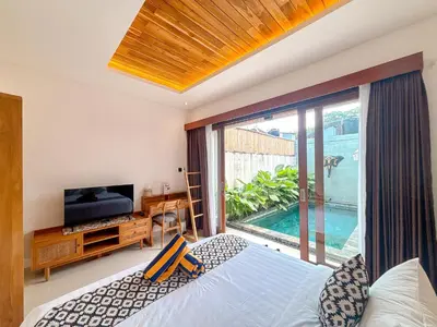 a bedroom with a bed and a tv and a large window at The Abian Villa Seminyak in Seminyak