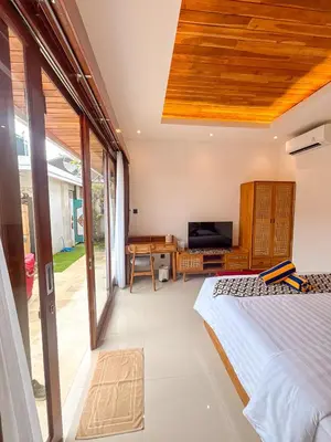 a bedroom with a bed and a desk and a television at The Abian Villa Seminyak in Seminyak