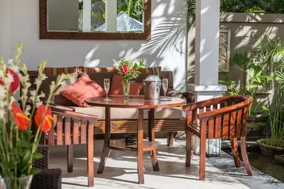 a wooden table with chairs and a couch at Villa Sedap Malam - Private 2 Bedroom Villa Near Seminyak Beach in Kuta