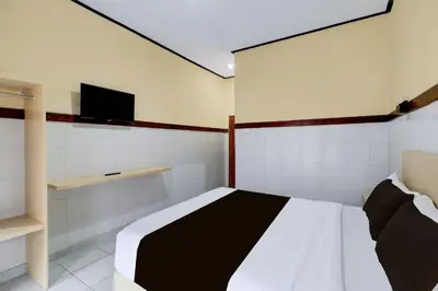 a bedroom with a bed and a tv on the wall at Townhouse Oak Legian Near Legian Beach Formerly Sayang Maha Merta in Legian