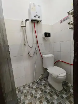 a bathroom with a toilet and a red hose at Pondok Mawar in Badung