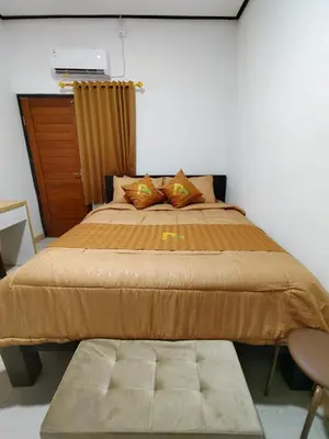 a bedroom with a large bed with a brown comforter at Pondok Mawar in Badung