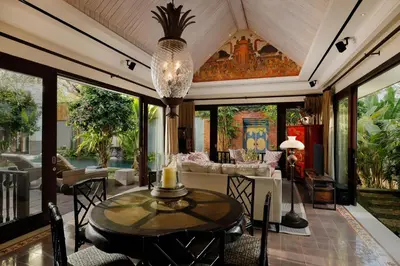 a living room with a table and a chandelier at Puri Tibo Tanjung Sanur in Sanur