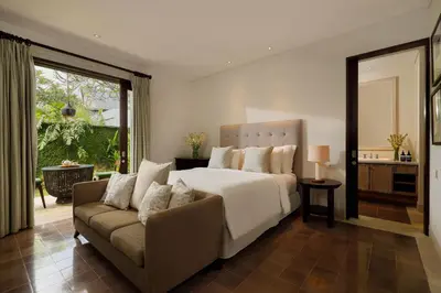 a bedroom with a large bed and a couch at Puri Tibo Tanjung Sanur in Sanur