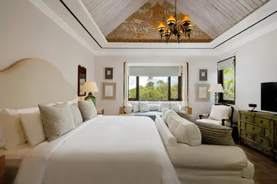 a bedroom with a large white bed and a couch at Puri Tibo Tanjung Sanur in Sanur