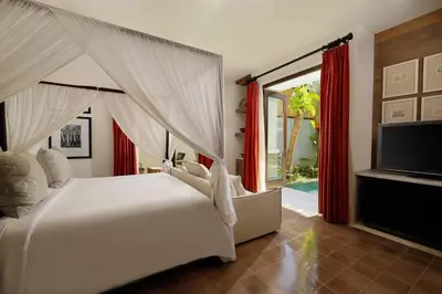 a bedroom with a white bed and a television at Puri Tibo Tanjung Sanur in Sanur
