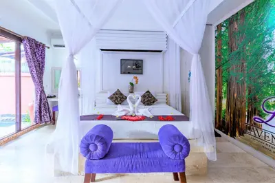 a bedroom with a large bed with purple chairs at Private Pool Villas Kuta Bali in Kuta