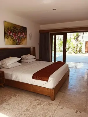 a bedroom with a large bed and a sliding glass door at Villa Louis Tanjung Benoa in Nusa Dua