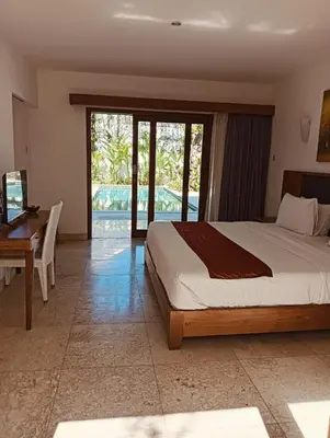 a bedroom with a large bed and a desk and a desk at Villa Louis Tanjung Benoa in Nusa Dua