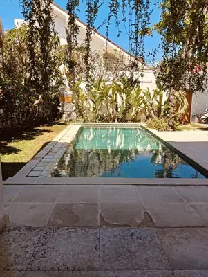 a swimming pool in front of a house at Villa Louis Tanjung Benoa in Nusa Dua