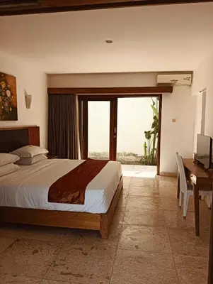 a bedroom with a bed and a desk and a window at Villa Louis Tanjung Benoa in Nusa Dua