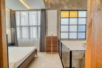 a bedroom with a bed and a desk and windows at Tuju Apartment 1BR Loft in Umalas in Canggu